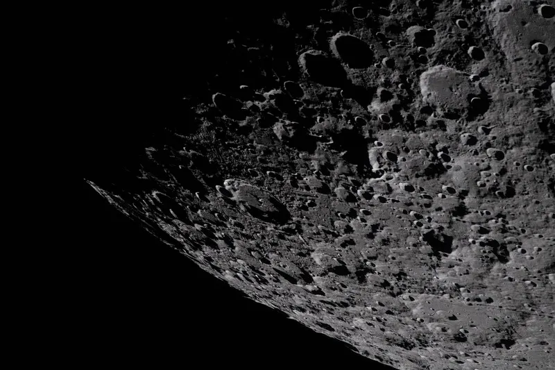 Artemis II crew photo of heavily cratered terrain near the lunar South Pole–Aitken basin, with the day–night terminator visible