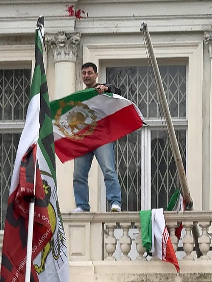 Protester replaces regime flag on Iranian embassy in London with pre-revolution national flag (cropped)