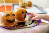 Kid pressing the eyes on a caramel apple jack o' lantern (15663506762)