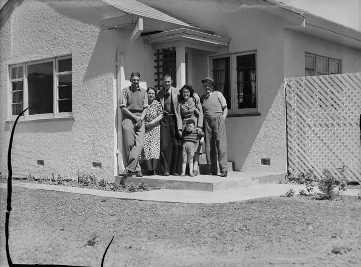 Full-length group portrait of four adults and a young boy in front of a house (AM 77018-1)