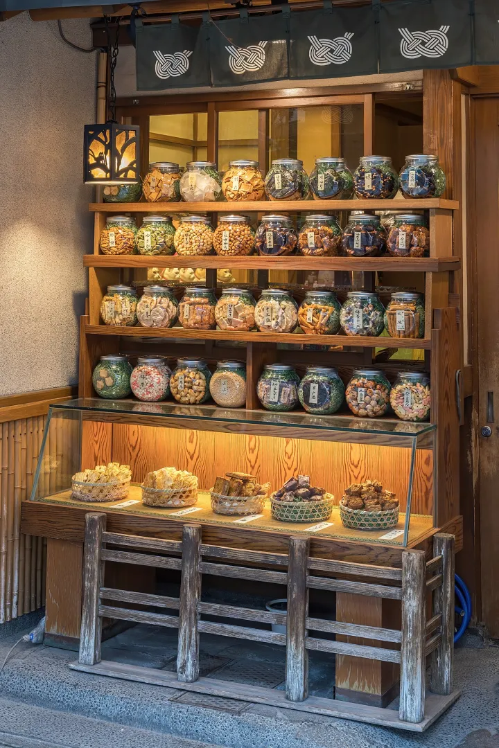 Illuminated wooden shelf with many glass jars containing cookies for sale in Tokyo