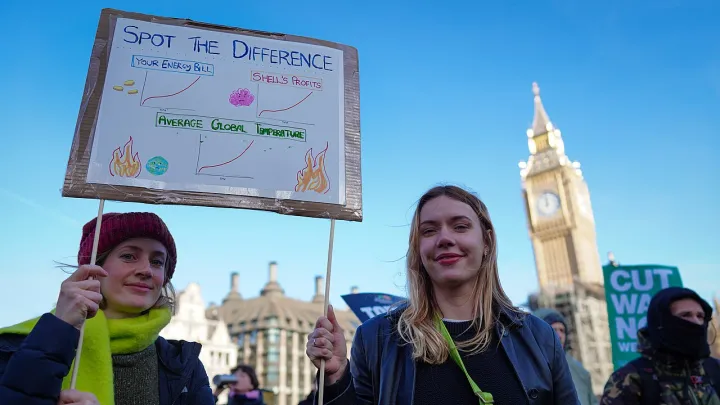 Two activists with a placard highlighting soaring energy prices, Shell's profits and average global temperatures
