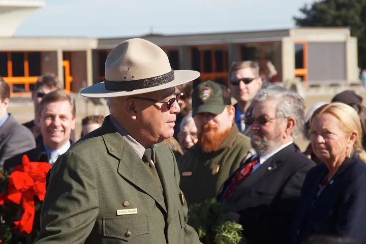 Park interpretive ranger Darrell Collins leads the wreath-laying ceremony during the 110th anniversary of the Wright brothers (5e06ea6a-1dd8-b71c-07c7-61076cb6b