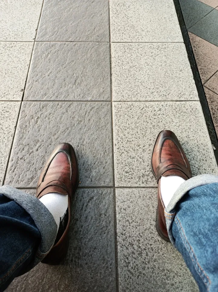 Self-photographed feet wearing a pair of Penny Loafers and a pair of denim pants